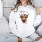 Scotland Highland Cow Hoodie in white, with the text Messy Hair Don't Care, being worn by a girl on a sofa, farmcore rural style.
