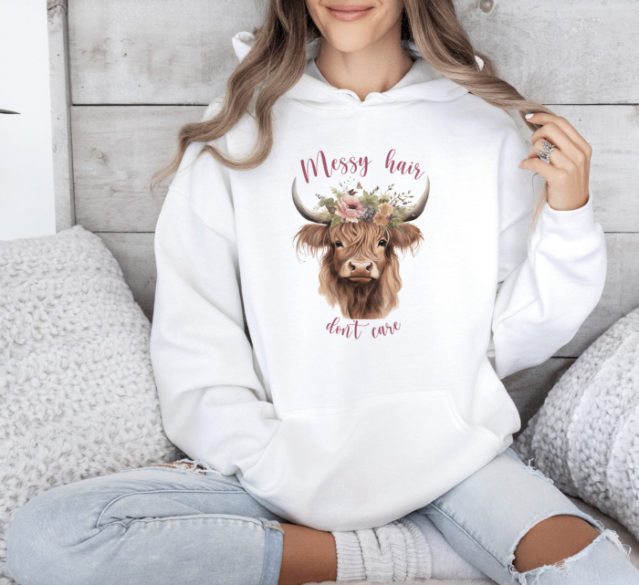 Scotland Highland Cow Hoodie in white, with the text Messy Hair Don't Care, being worn by a girl on a sofa, farmcore rural style.